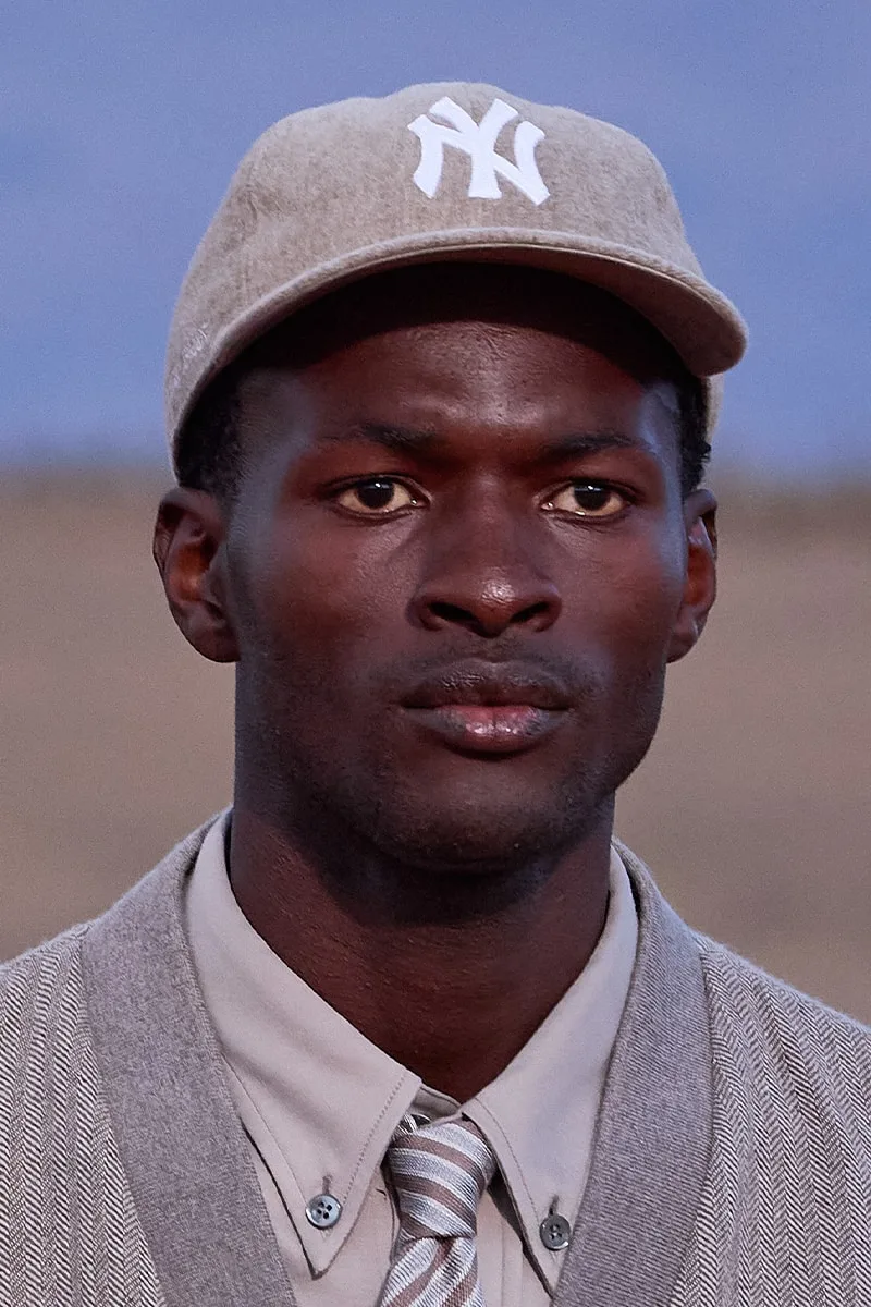 Portrait d'homme avec casquette et tenue élégante, extérieur.