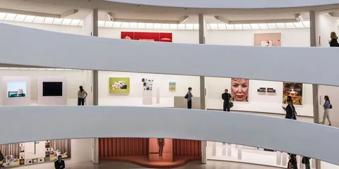 Intérieur d'une galerie d'art moderne avec des visiteurs et des œuvres d'art exposées.
