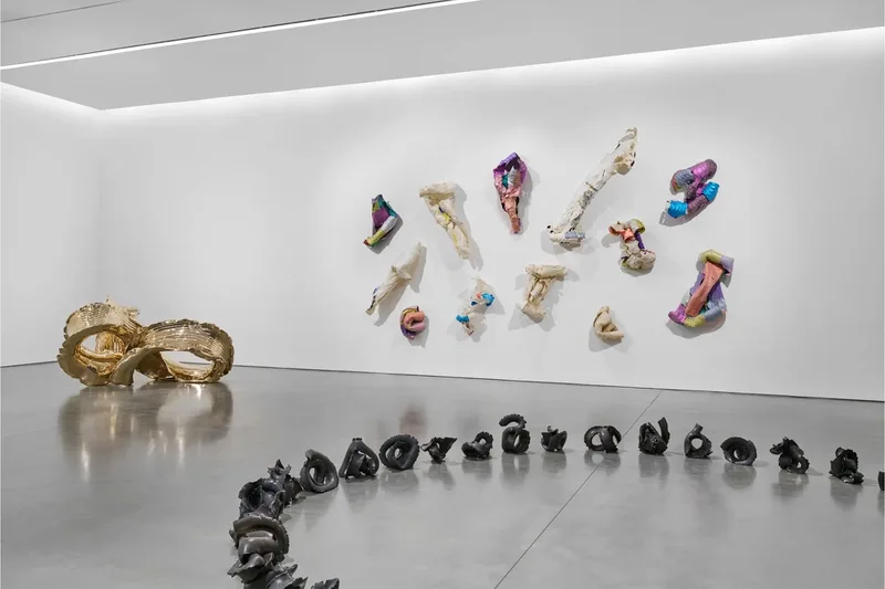Galerie moderne avec sculptures abstraites au sol et murales.