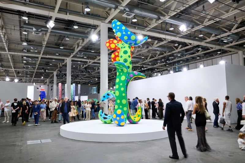 Exposition artistique avec sculpture colorée et foule de visiteurs