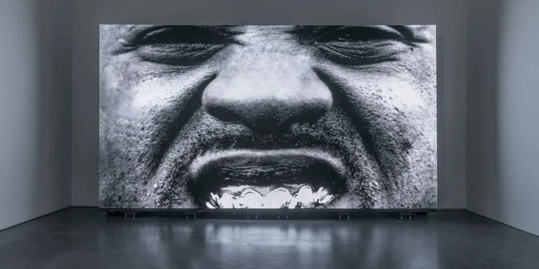 Image en noir et blanc d'un visage, bouche ouverte, en gros plan.
