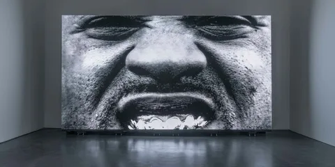 Image en noir et blanc d'un visage, bouche ouverte, en gros plan.