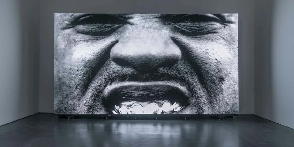 Image en noir et blanc d'un visage, bouche ouverte, en gros plan.