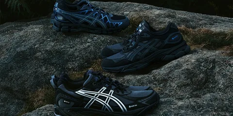 Trois paires de baskets noires et bleues sur un rocher.