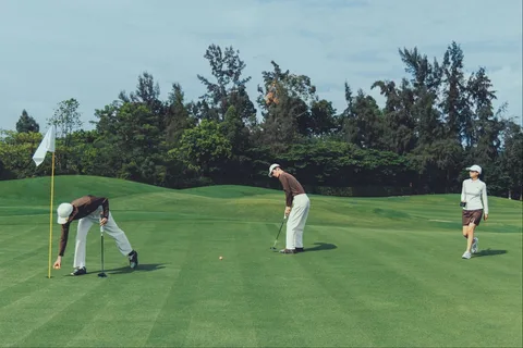 Trois golfeurs sur un green, prêt à frapper la balle.