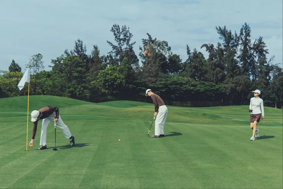 Trois golfeurs sur un green, prêt à frapper la balle.