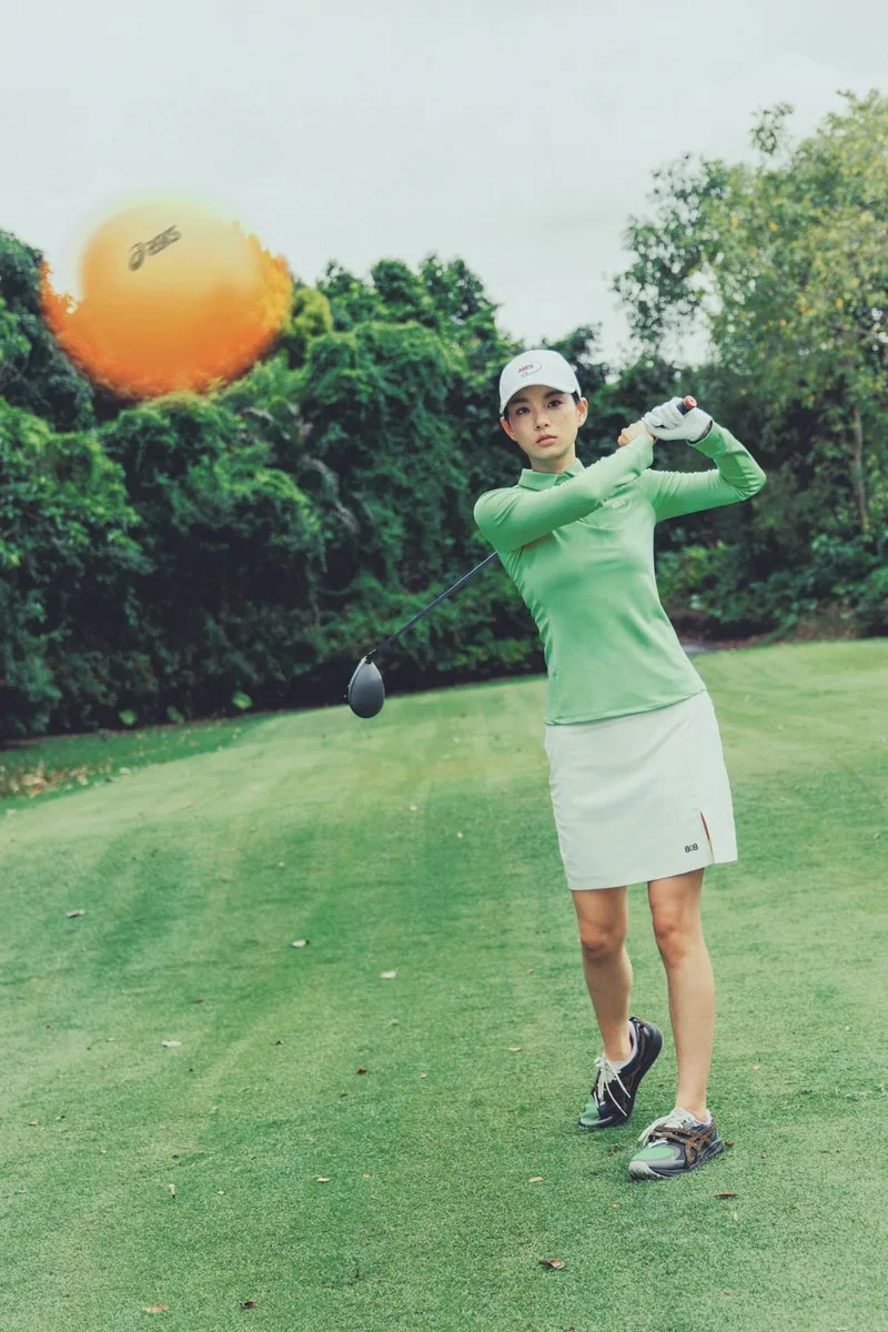 Femme jouant au golf sur un parcours verdoyant.