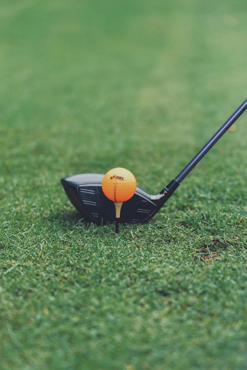 Club de golf frappant une balle orange sur le gazon