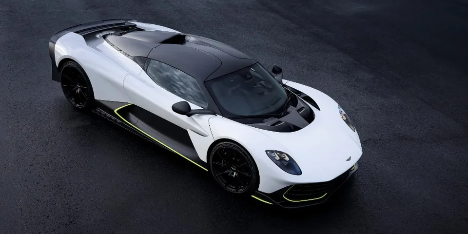 Voiture de sport blanche et noire avec accents jaunes sur fond sombre.