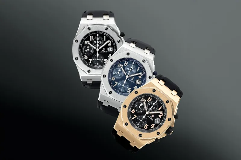 Trois montres de luxe sur fond gris.