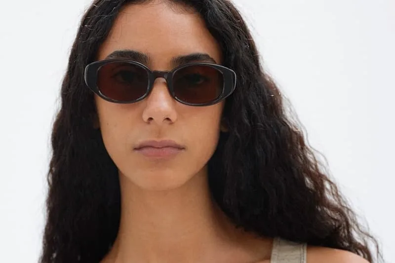 Femme avec lunettes de soleil et longs cheveux bouclés, fond blanc