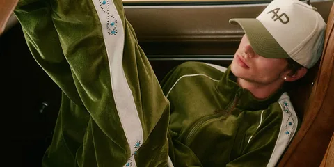 Personne vêtue de vert avec casquette dans un intérieur de voiture.