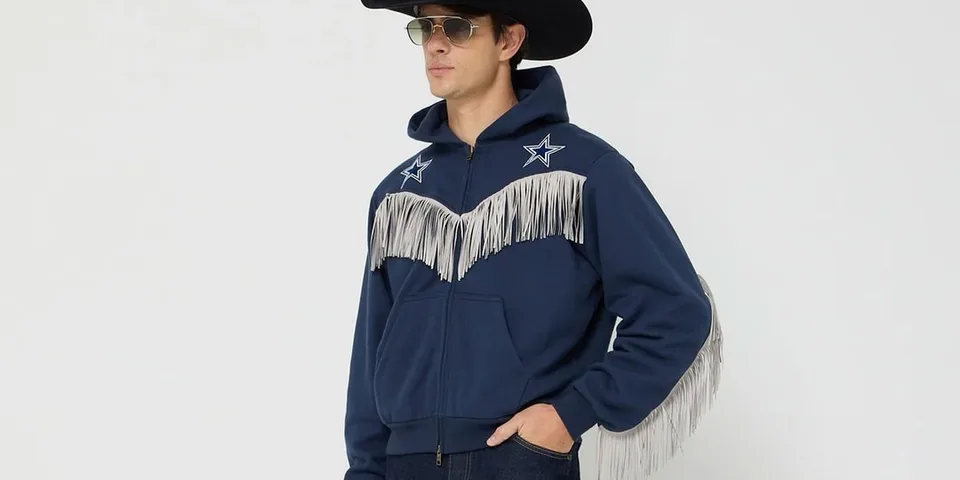 Homme avec sweat à capuche bleu et franges, chapeau noir.