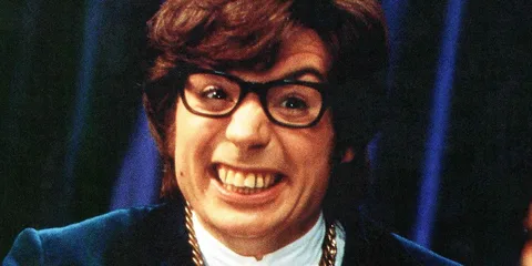 Homme avec lunettes souriant largement, costume bleu.
