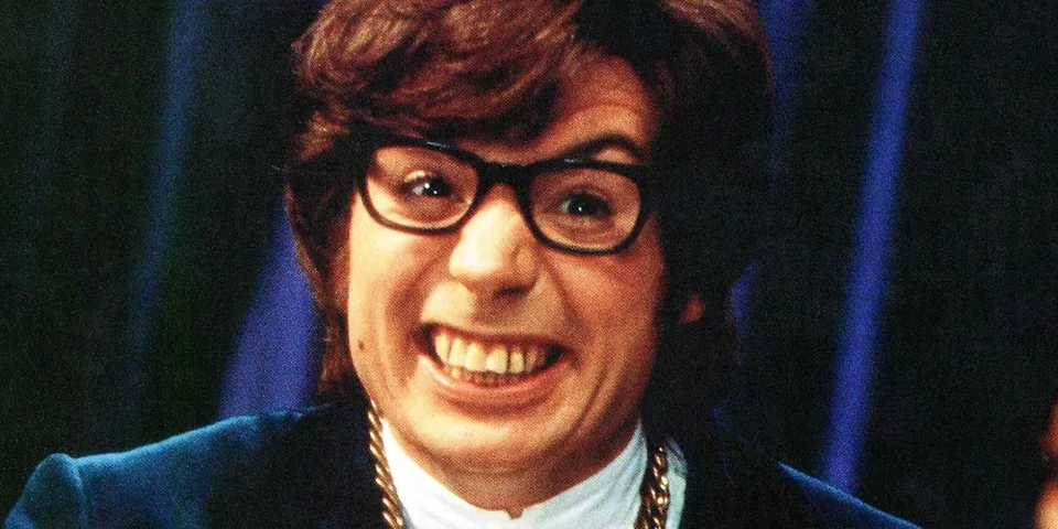 Homme avec lunettes souriant largement, costume bleu.