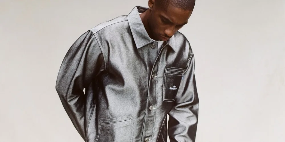 Homme portant une veste gris métallisé, regardant vers le bas.