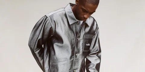 Homme portant une veste gris métallisé, regardant vers le bas.