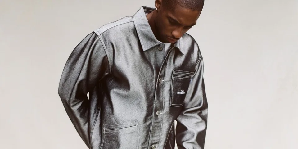 Homme portant une veste gris métallisé, regardant vers le bas.