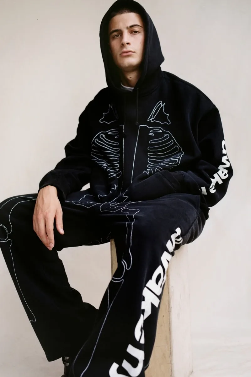 Homme en survêtements noirs avec motif de squelette.