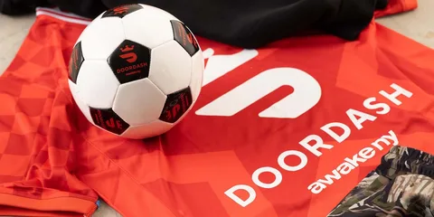 Ballon de football et maillot rouge avec logos Doordash et awakeny.