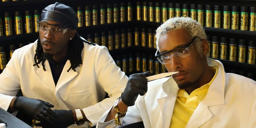 Deux personnes en blouse blanche dans un laboratoire de parfumerie.