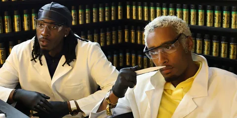 Deux personnes en blouse blanche dans un laboratoire de parfumerie.