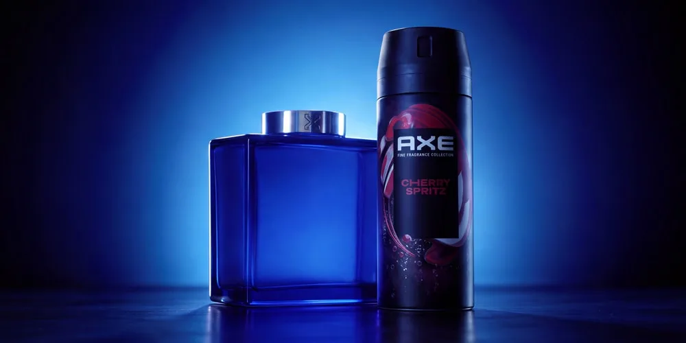 Bouteille bleu et déodorant AXE Cherry Spritz sur fond bleu.