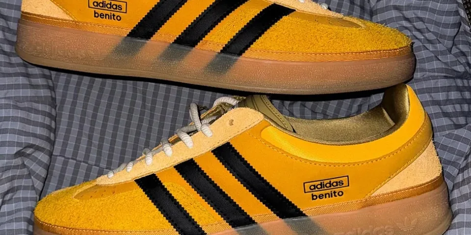 Chaussures adidas jaunes avec rayures noires et semelles en caoutchouc visibles.