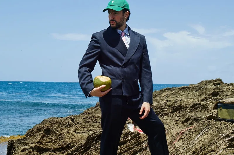 Homme en costume avec casquette verte tenant une noix de coco près de la mer