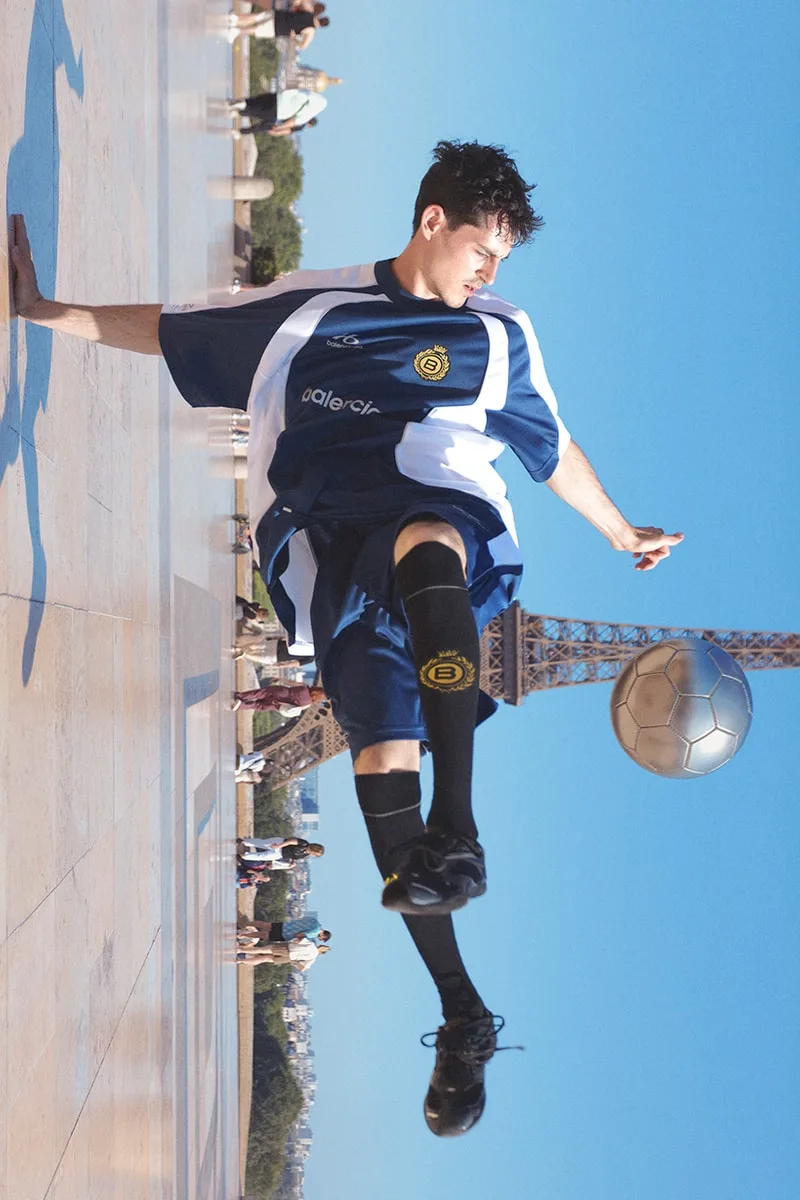Joueur en action devant la Tour Eiffel, ballon et maillot de foot.