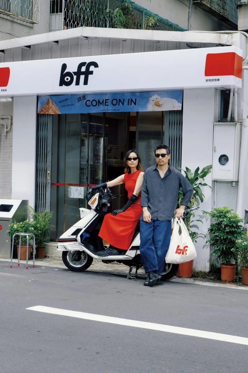 Personnes posant devant un magasin avec un scooter.