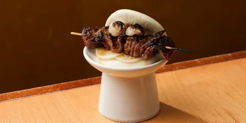Brochette de viande dans un bao sur un support blanc.