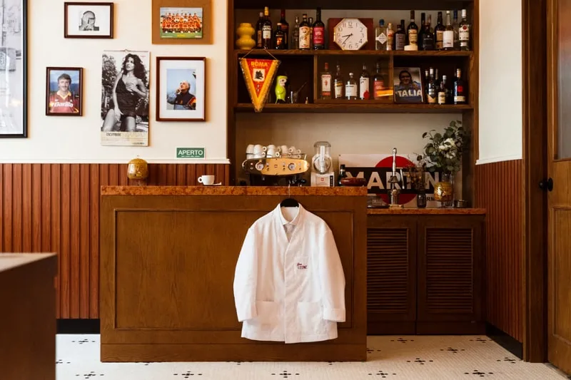 Intérieur avec un manteau blanc, des étagères avec des bouteilles et des photos.