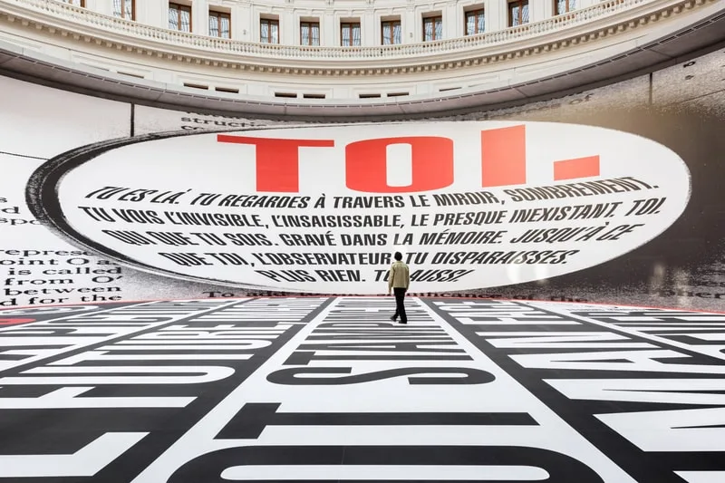 Installation artistique avec texte géant sur murs et sol.