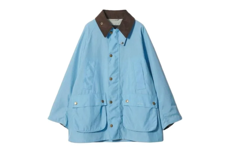 Veste bleu ciel avec col marron et boutons-pression dorés.