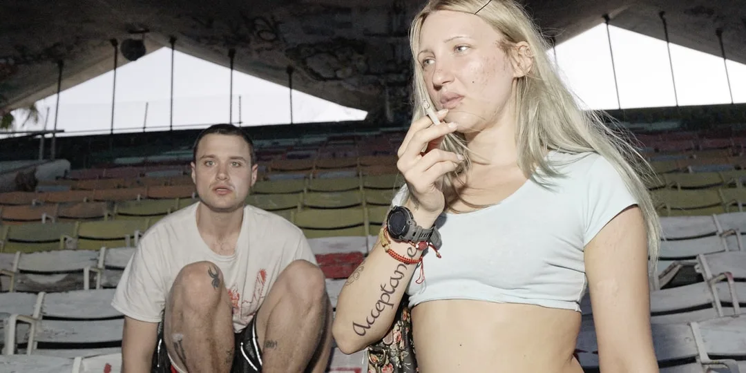 Deux jeunes assis dans un amphithéâtre abandonné, la femme tenant une cigarette.
