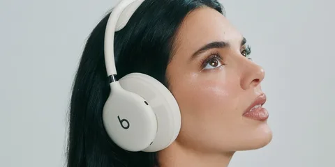 Femme portant un casque audio blanc et regardant vers le haut.