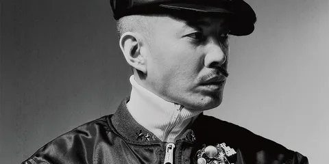 Portrait en noir et blanc d’un homme portant une casquette et une veste sombre.