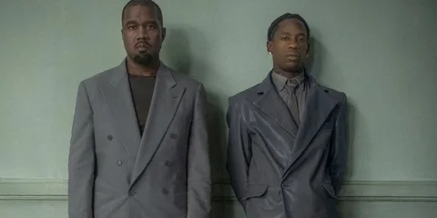 Deux hommes en costumes gris devant un fond vert.