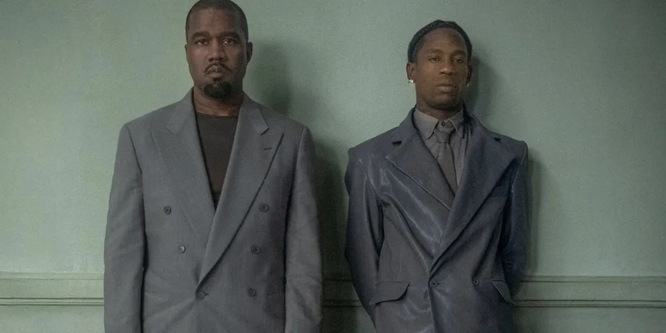 Deux hommes en costumes gris devant un fond vert.
