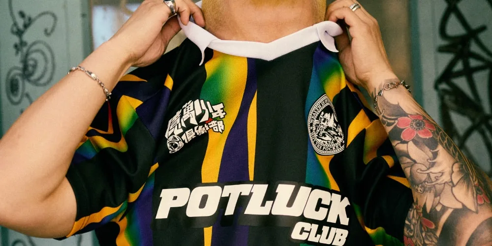 Personne portant un maillot coloré avec 'POTLUCK CLUB' et des motifs graphiques.