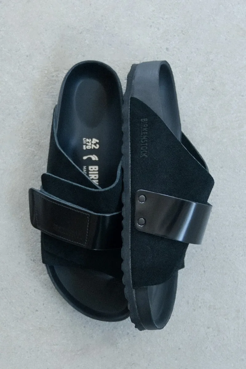 Sandales noires Birkenstock sur fond gris.