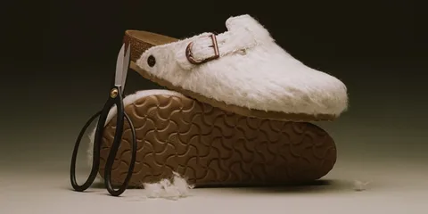Chaussure en peluche blanche avec semelle brune et ciseaux noirs.