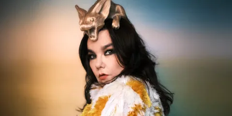 Femme avec une coiffure unique et manteau coloré, fond flou.