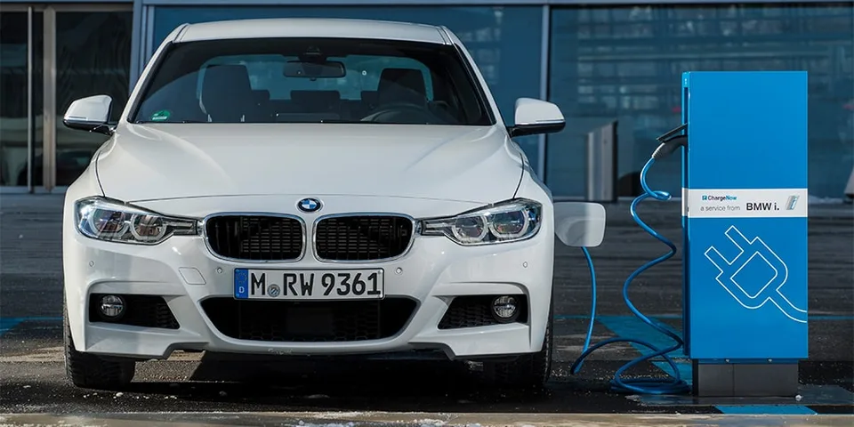 Voiture blanche BMW avec station de recharge électrique.