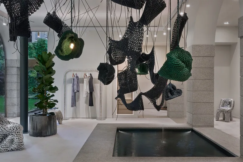 Installation artistique avec sculptures suspendues et bassin d'eau, intérieur moderne.