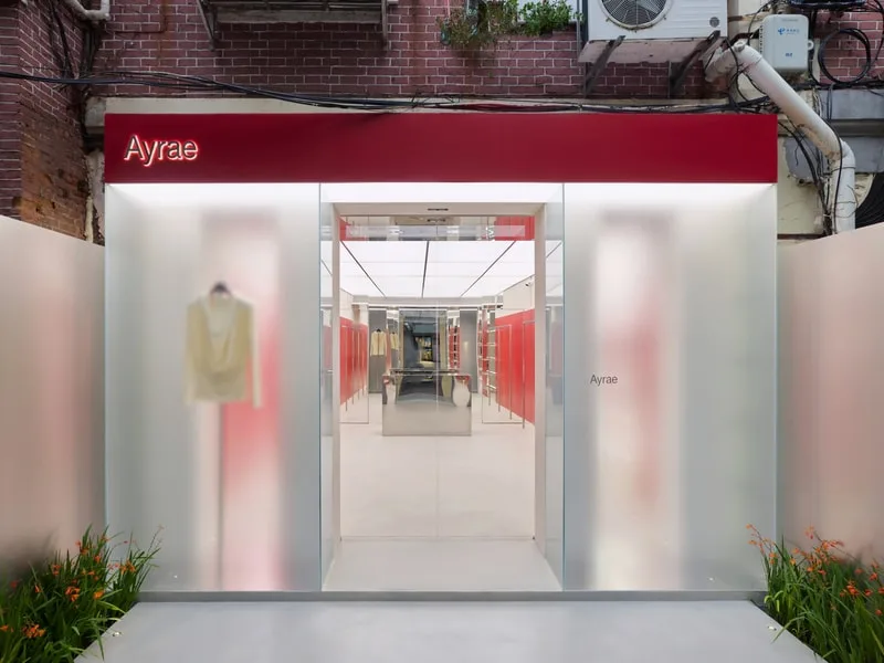 Entrée de boutique moderne avec panneau rouge et plantes.