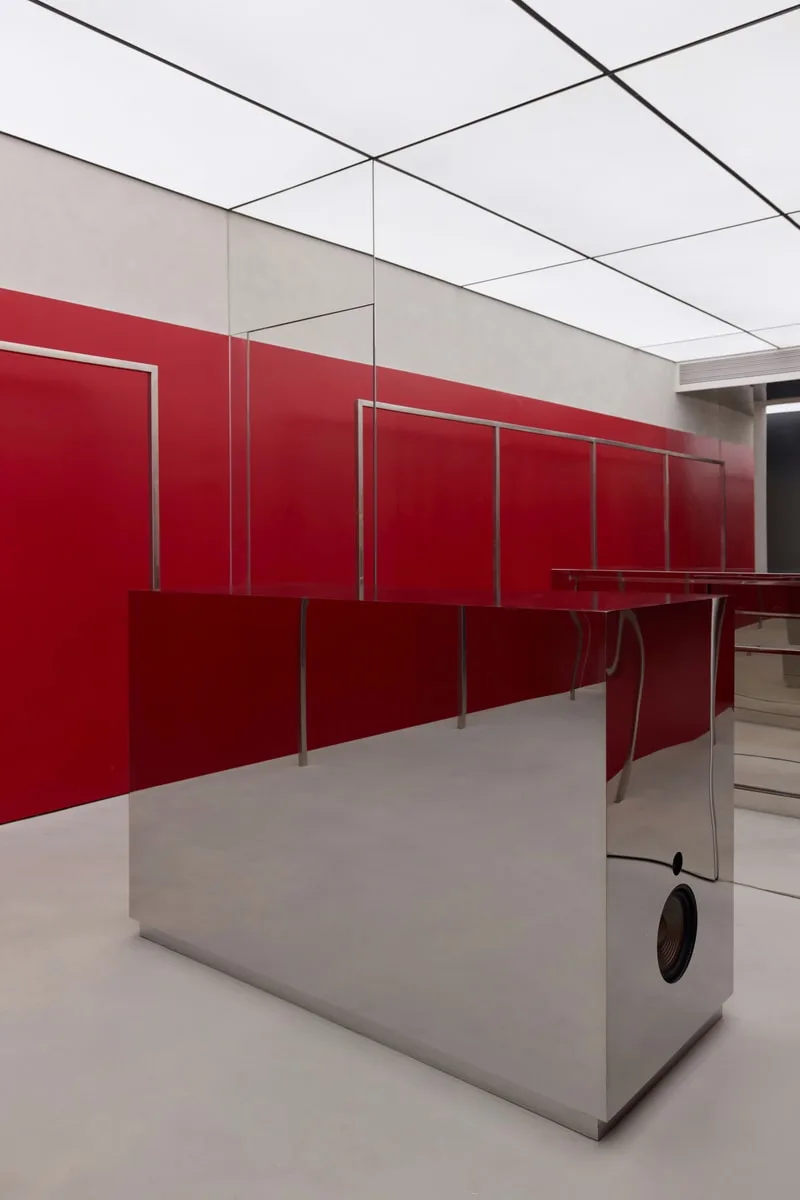 Intérieur moderne avec murs rouges et surfaces réfléchissantes.