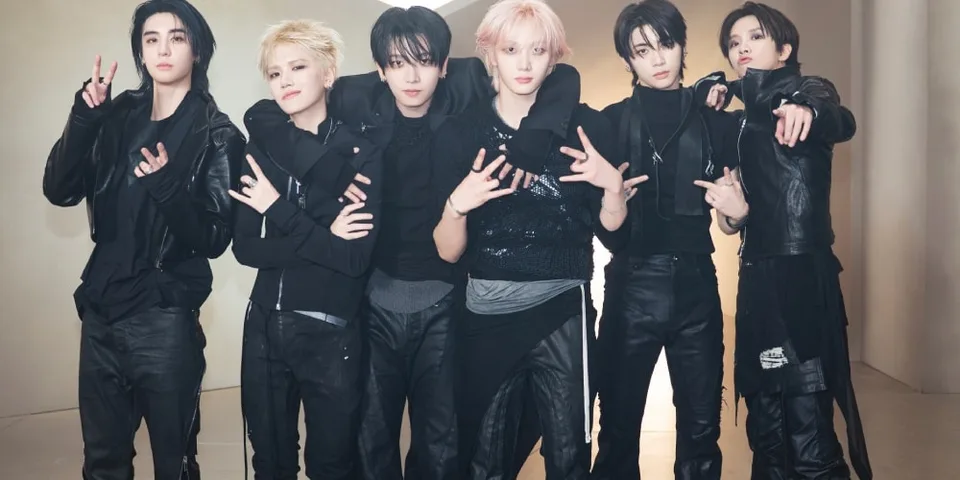 Groupe de jeunes hommes en vêtements noirs posant ensemble.