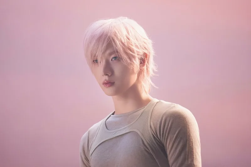 Personne aux cheveux roses devant un fond rose.